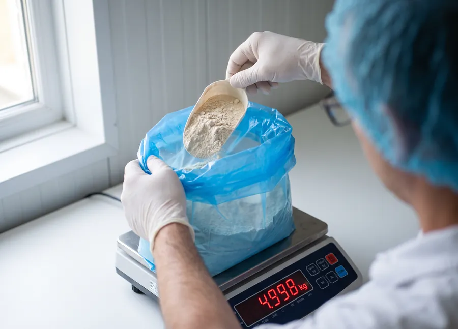 Operator weighing a lined bag of blended powder on a bench scale